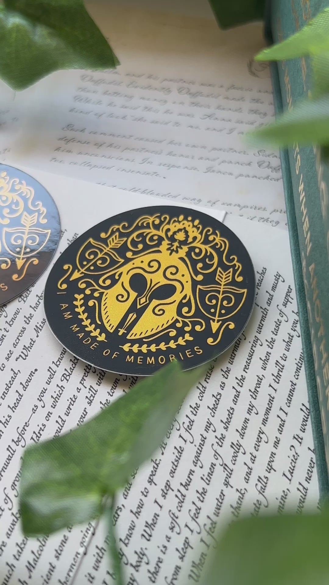 Video of No One Designs Song of Achilles inspired sticker set showcasing the matte and gloss stickers side by side against book page background.