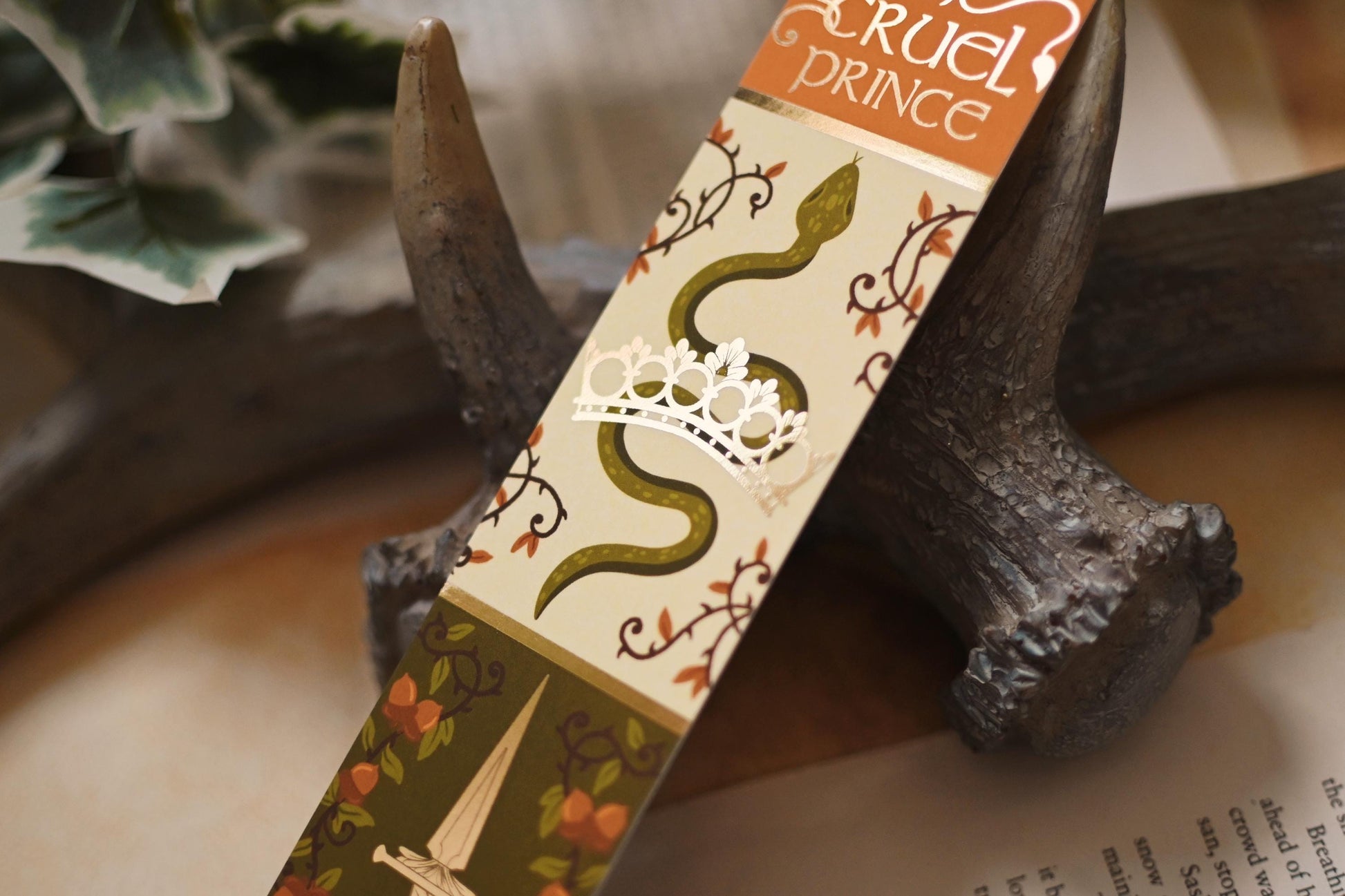 A close up shot of No One Designs Cruel Prince inspired bookmark showcasing the snake and gold-foil crown detail.
