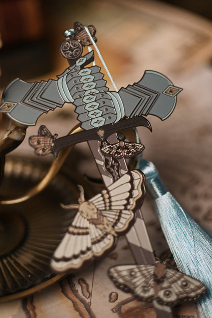Decorative bookmark inspired by The Knight and The Moth by Rachel Gillig with intricate design and tassel on a blurred background