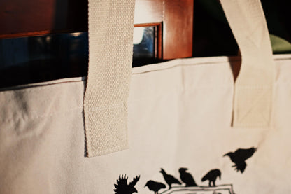 A close up photograph of the Six of Crows Crow Club inspired tote bag showcasing the dtailing of the staps and how they are secured. 