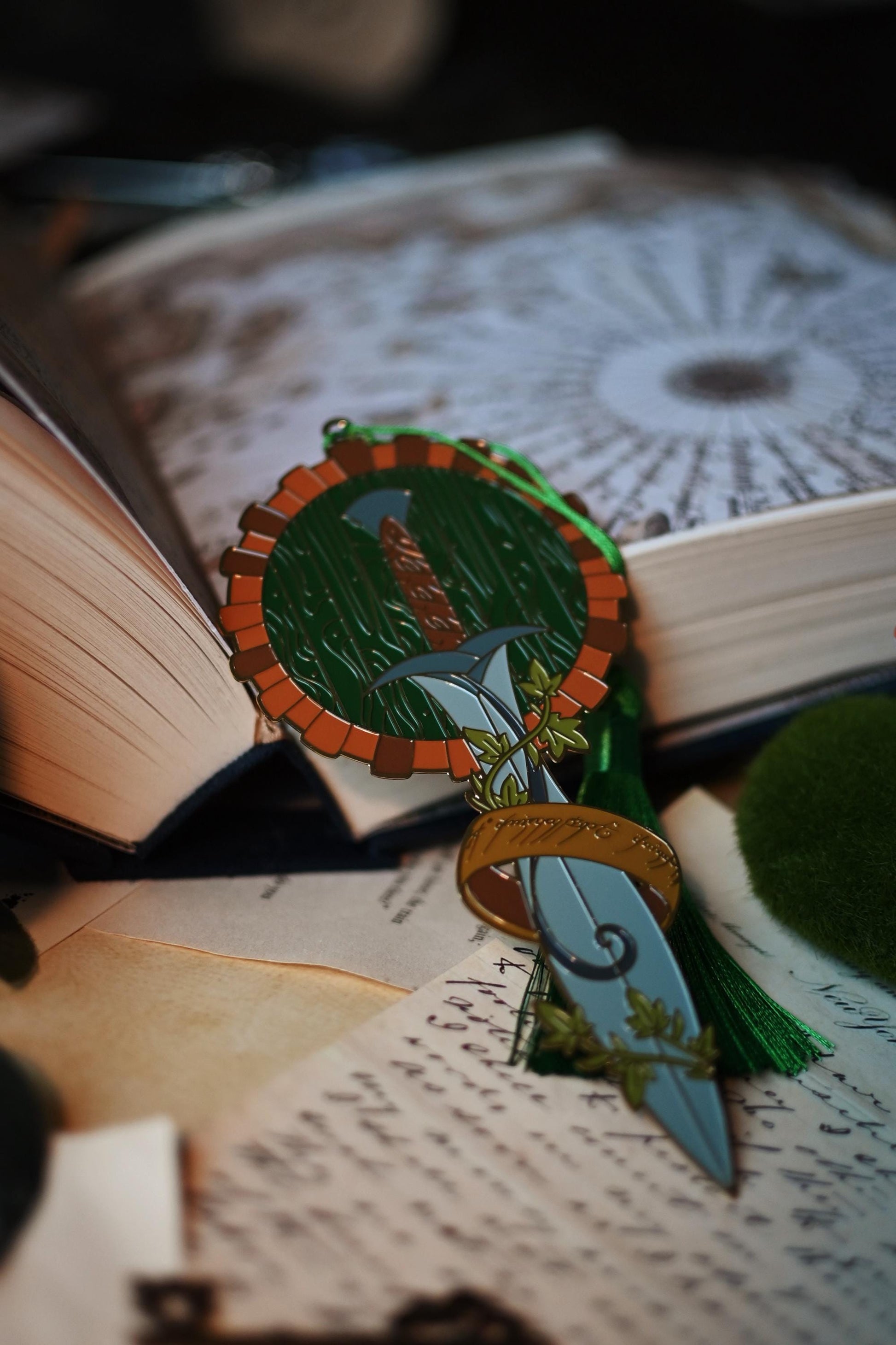 No0neDesigns The Hobbit inspired bookmark featuring Bilbo Baggins' front door to his hobbit hole, his sword sting and the one ring. The bookmark is propped up against the book and showcases green tassel bookmark.