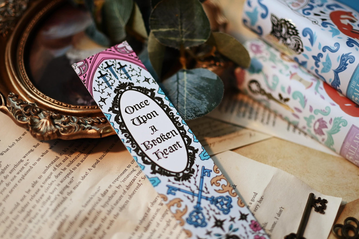 Inspired by the books by Stephanie Garbar, the Once Upon a Broken Heart bookspine bookmark rests against a background of the books, bookpages and propped up by a mirror. 