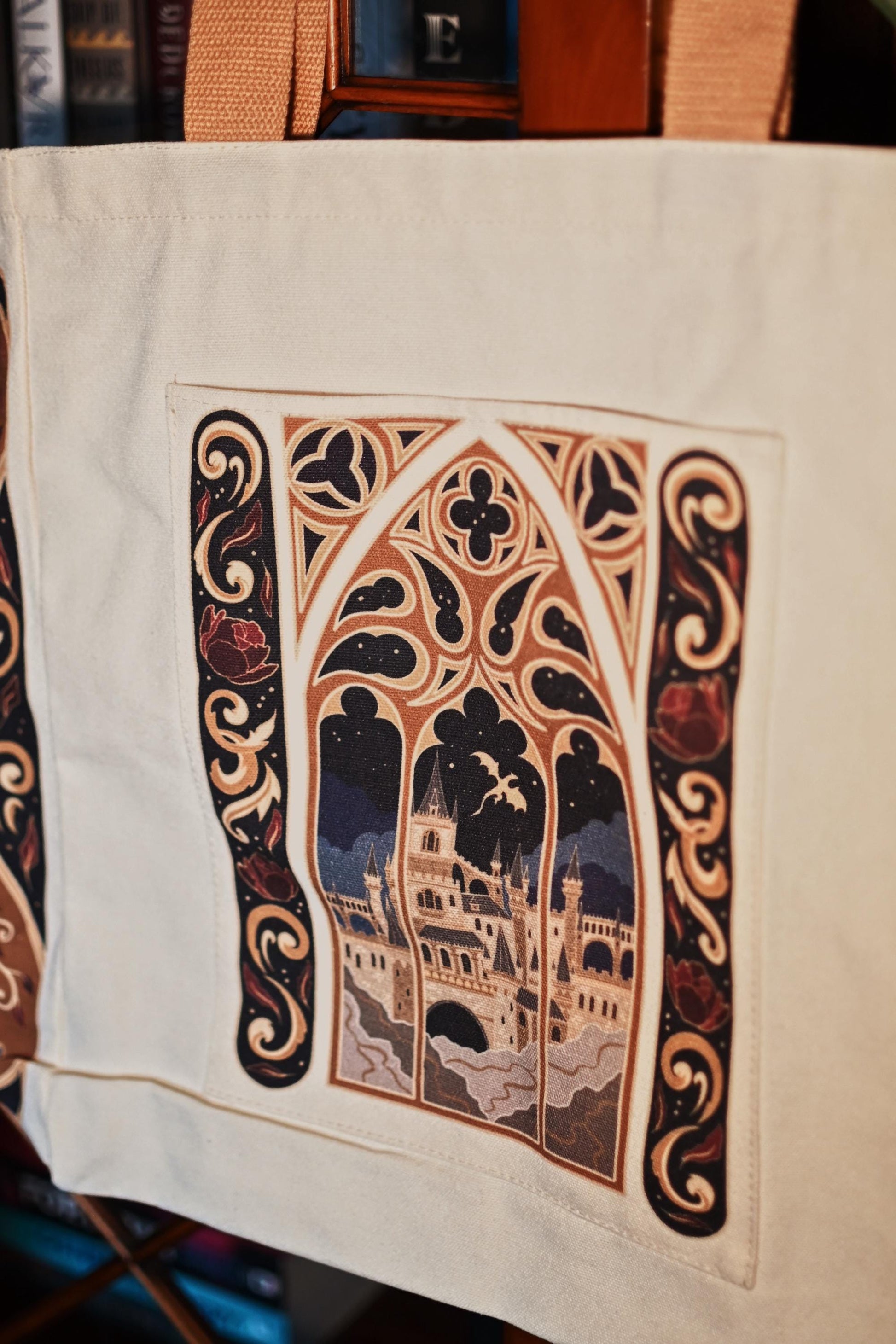 Close up image of the fantasy book bag, showcasing the window design looking out onto a window with a view of a castle and dragon flying in the sky.