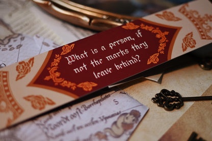 A Darker Shade of Magic bookmark featuring the reverse side with an alternative quote from The Invisible Life of Addie LaRue by VE Schwab: What is a person if not the marks they leave behind? 