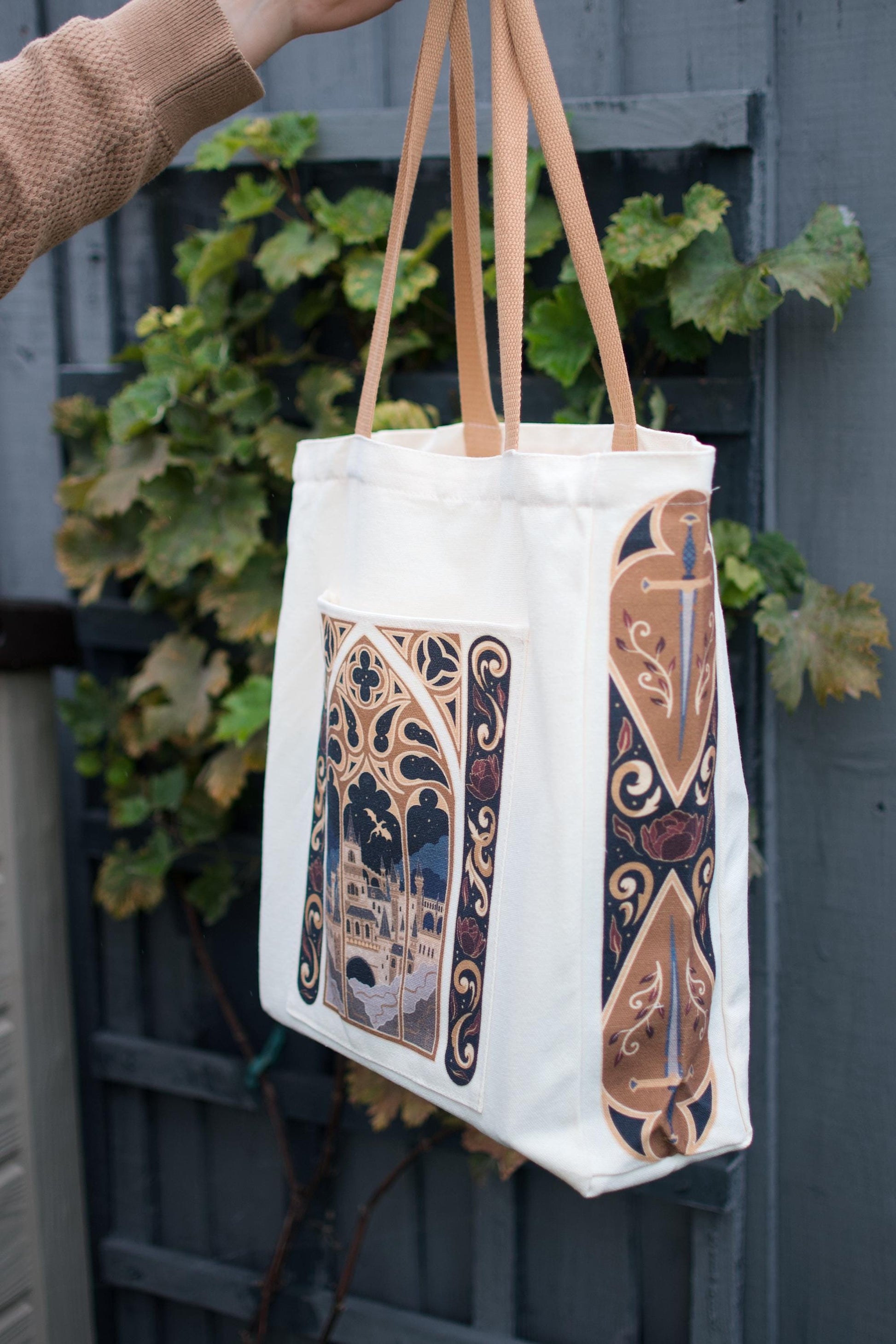 Chloe holding up the Fantasy Window Book Bag against a blue background. The side view showcases the front and side design of the fantasy window style.