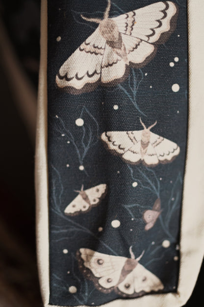 Side panel close up image of the Knight and the Moth book tote bag showcasing the moth pattern on a dark background.
