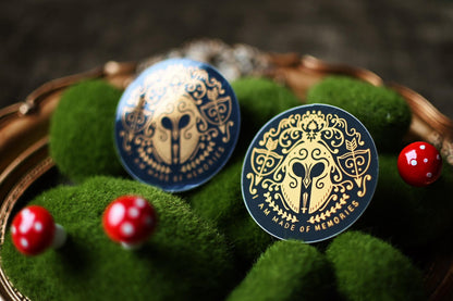 The No One Designs Song of Achilles stickers placed on a bed of fake moss to showcase the matte and gloss designs. 