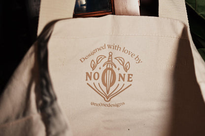A close up photograph of the inside of The Crow Club tote bag inspired by Leigh Bardugo's Six of Crows showcasing the print of the No One Designs logo. 